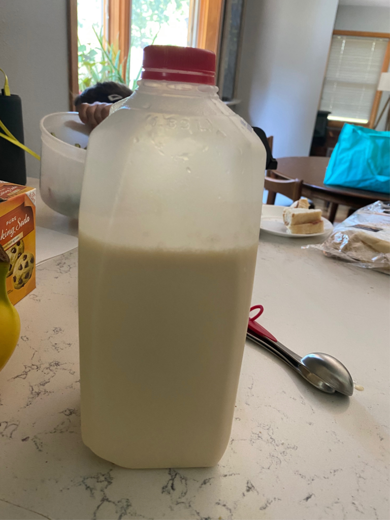 This simple hack shows a plastic half gallon milk jug filled 3/4 with pancake batter. 