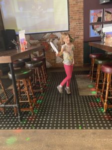Image of girl dancing between two sets of tables.